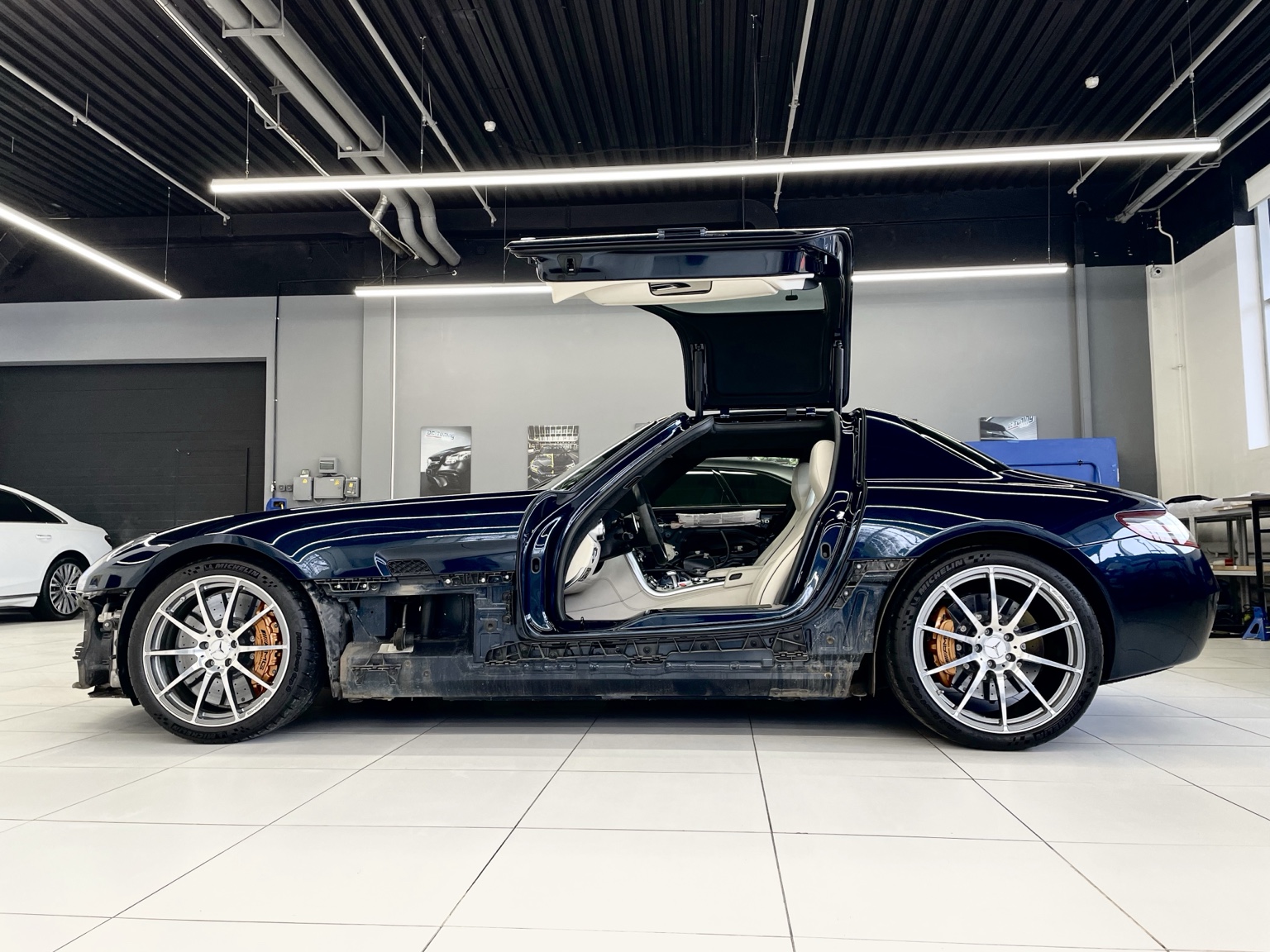 Dark blue Mercedes-Benz SLS AMG with its gullwing door open in the workshop